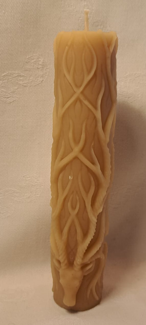 Decorative candle with a deer head design of multiple branching antlers on a beige background