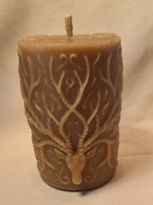 Decorative candle with a deer head design of multiple branching antlers on a beige background