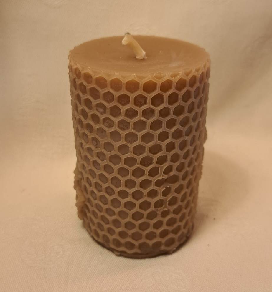 Beeswax candle with honeycomb pattern on a beige background