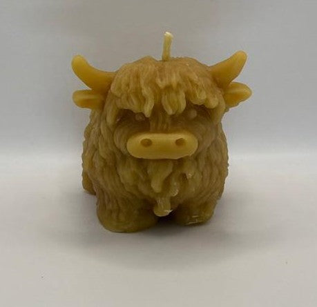 Beeswax candle shaped like a standing highland cow on a white background