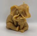 Beeswax candle shaped like mother elephant embracing baby elephant on a white background