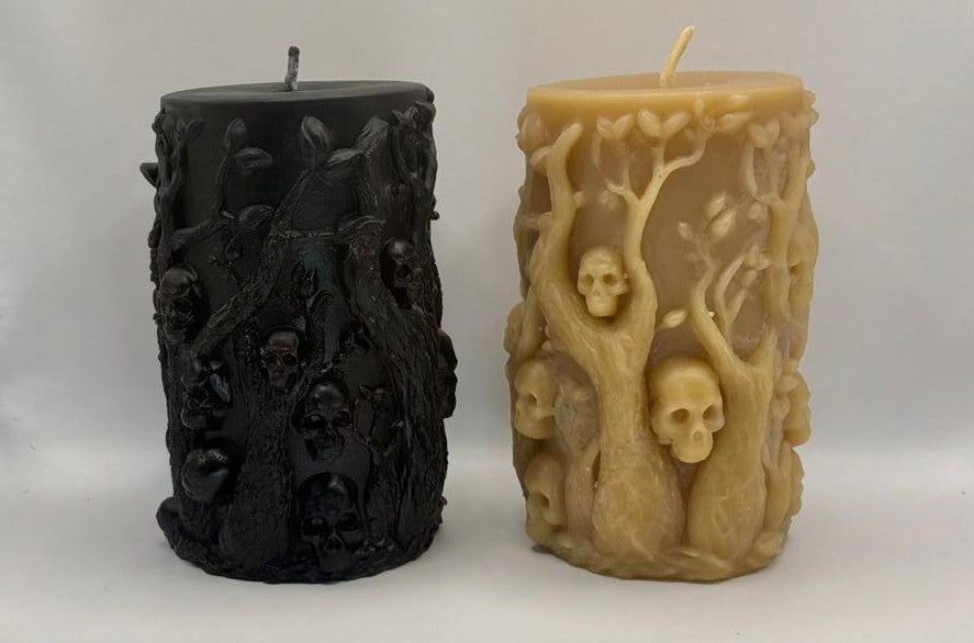 The back view of two intricately designed candles, one black and one natural beeswax, on a white background.